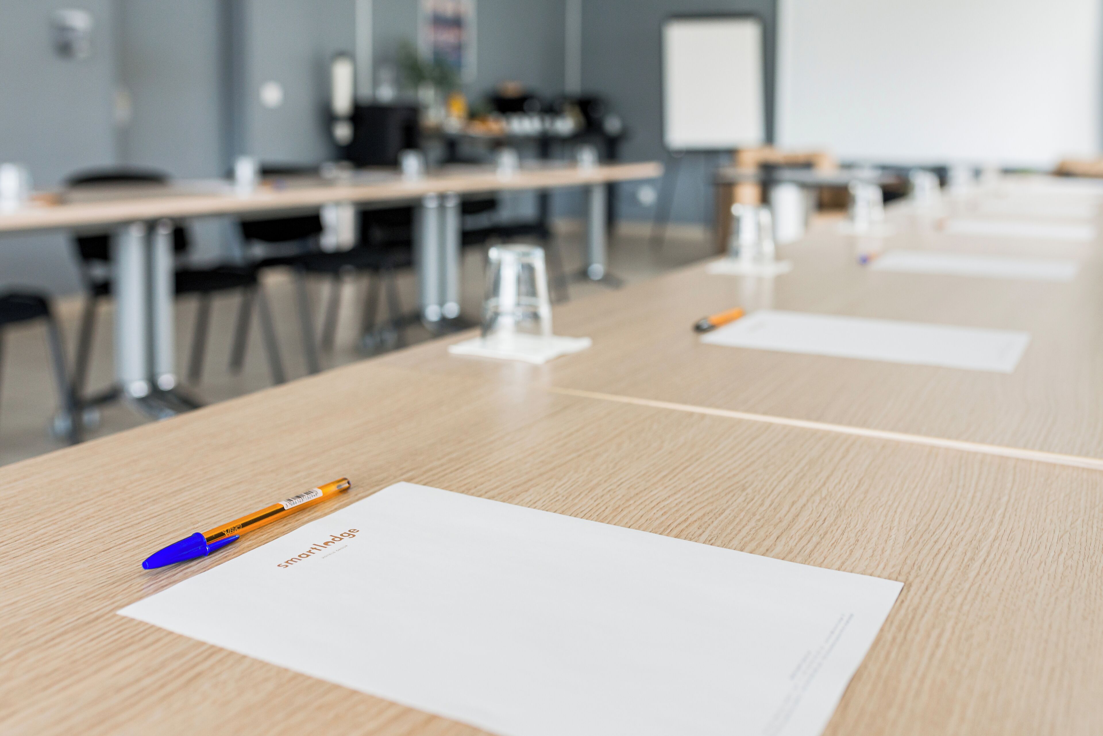 A conference room with a long table, chairs, and a whiteboard in the background.