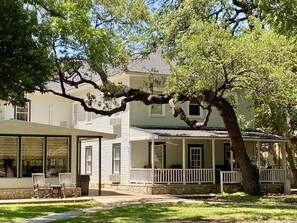 A two-story house with a covered porch, stone foundation, and large windows. - Inn On The River (Glen Rose)