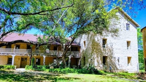 A two-story building with a balcony and a stone facade. - Inn On The River (Glen Rose)