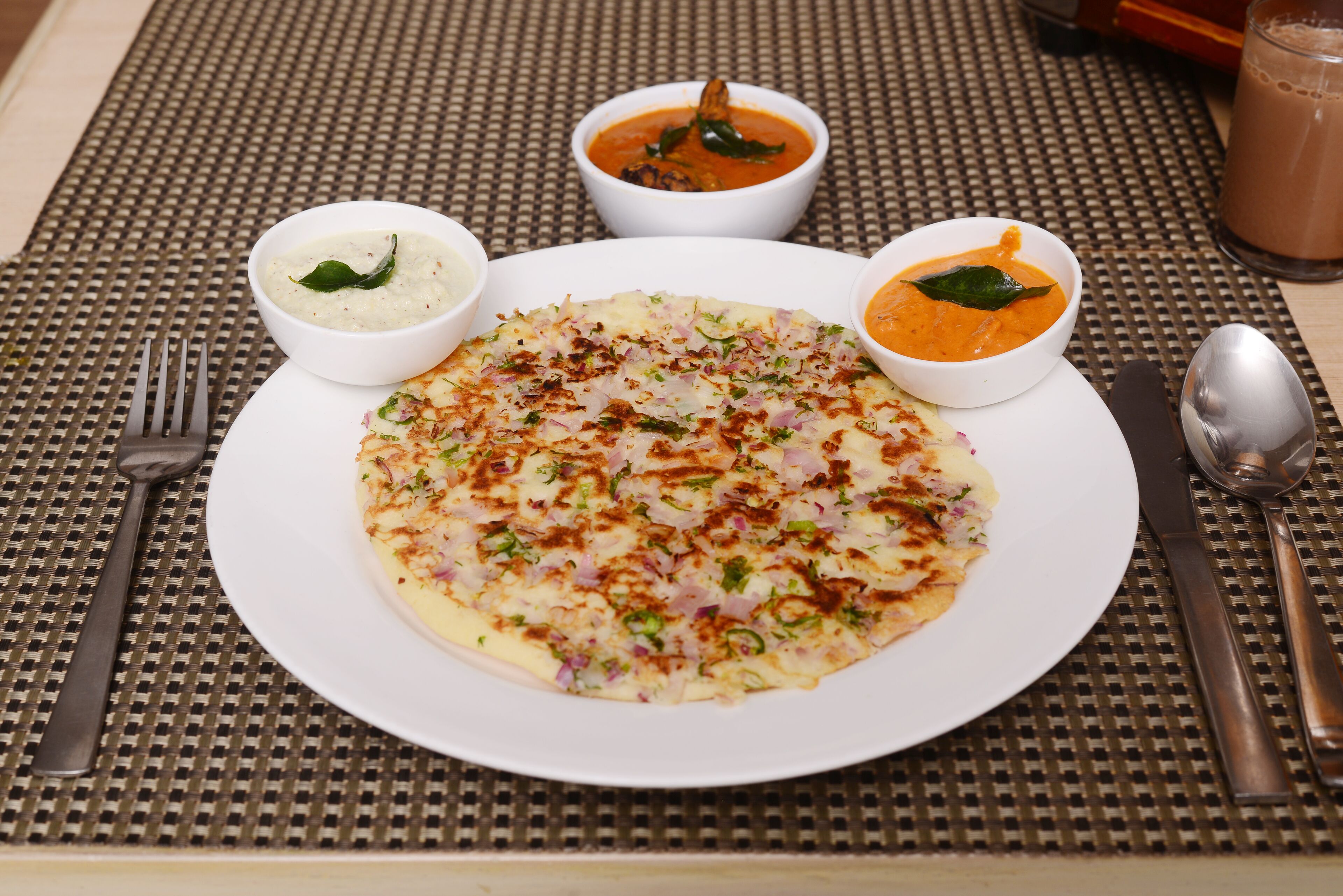 A plate of food with two bowls of soup and a glass of beverage on a table.