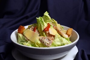 A bowl of salad with lettuce, croutons, and cheese on a white plate. - The Hawaii Comforts (Panaji)