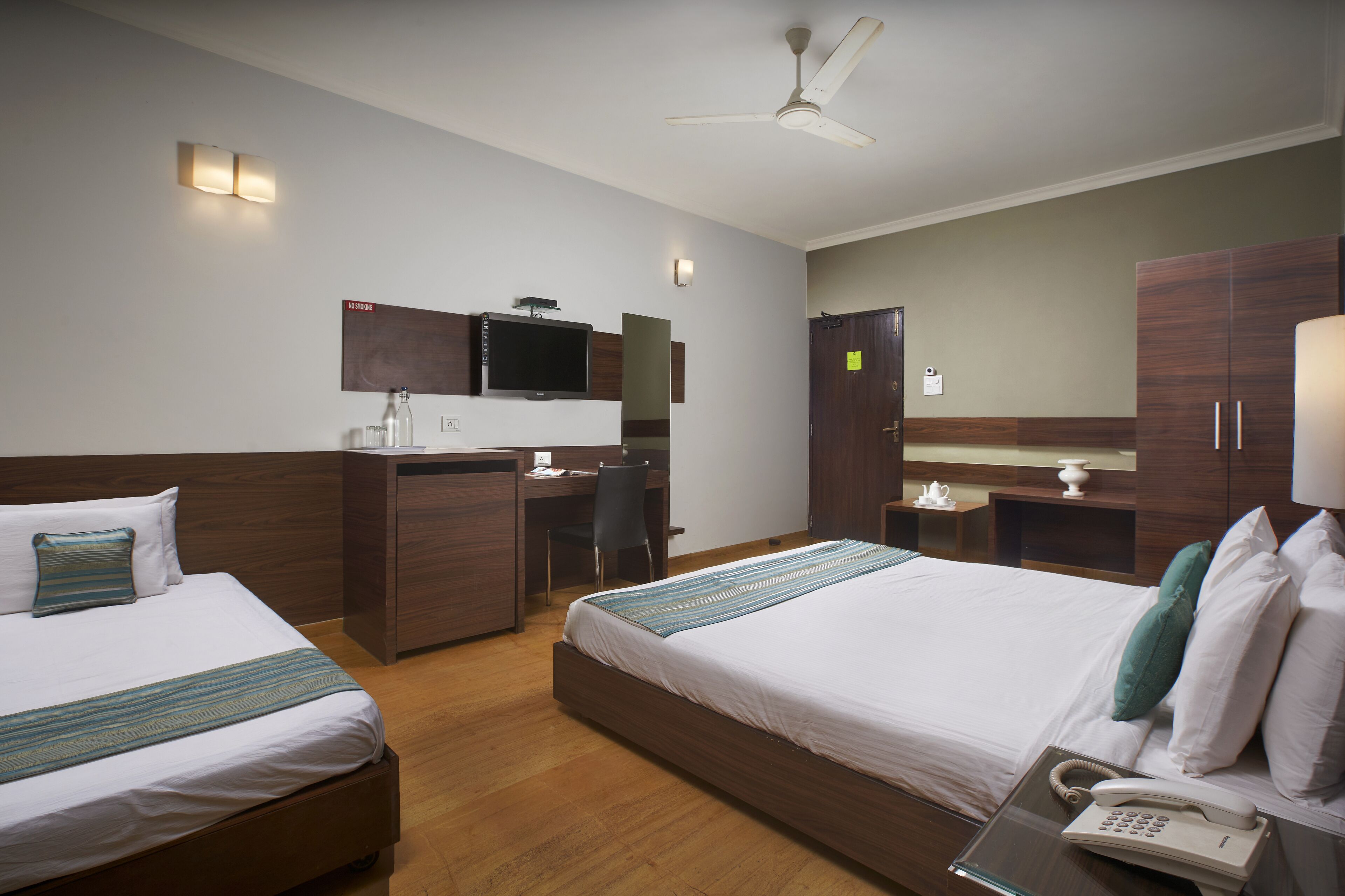 Une chambre d’hôtel avec deux lits, un bureau, une télévision et un téléphone.