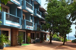 A multi-story hotel with balconies, potted plants, and a view of the ocean. - The Hawaii Comforts (Panaji)