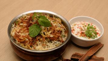 Eine Schüssel Biryani mit Minzblättern und dazu Raita.