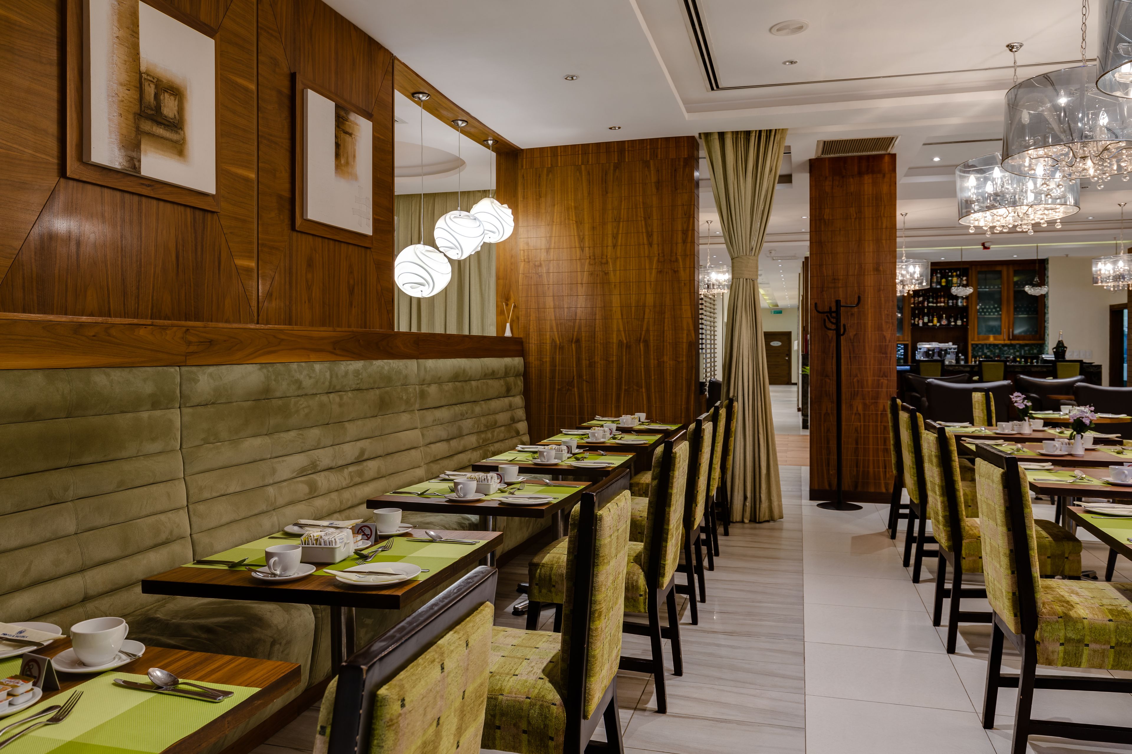 A restaurant with long tables, chairs, and a bar area.