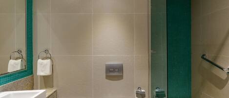 Une salle de bain moderne avec un lavabo blanc, des toilettes et une douche à parois de verre.