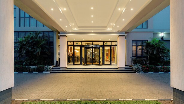 A hotel entrance with a revolving door, a brick-paved entrance, and a well-lit interior visible through the glass doors. - Protea Hotel by Marriott Benin City Select Emotan (Benin City)