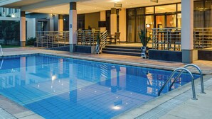 A hotel pool area with a clear blue pool, a covered seating area, and a staircase leading to the upper level. - Protea Hotel by Marriott Benin City Select Emotan (Benin City)