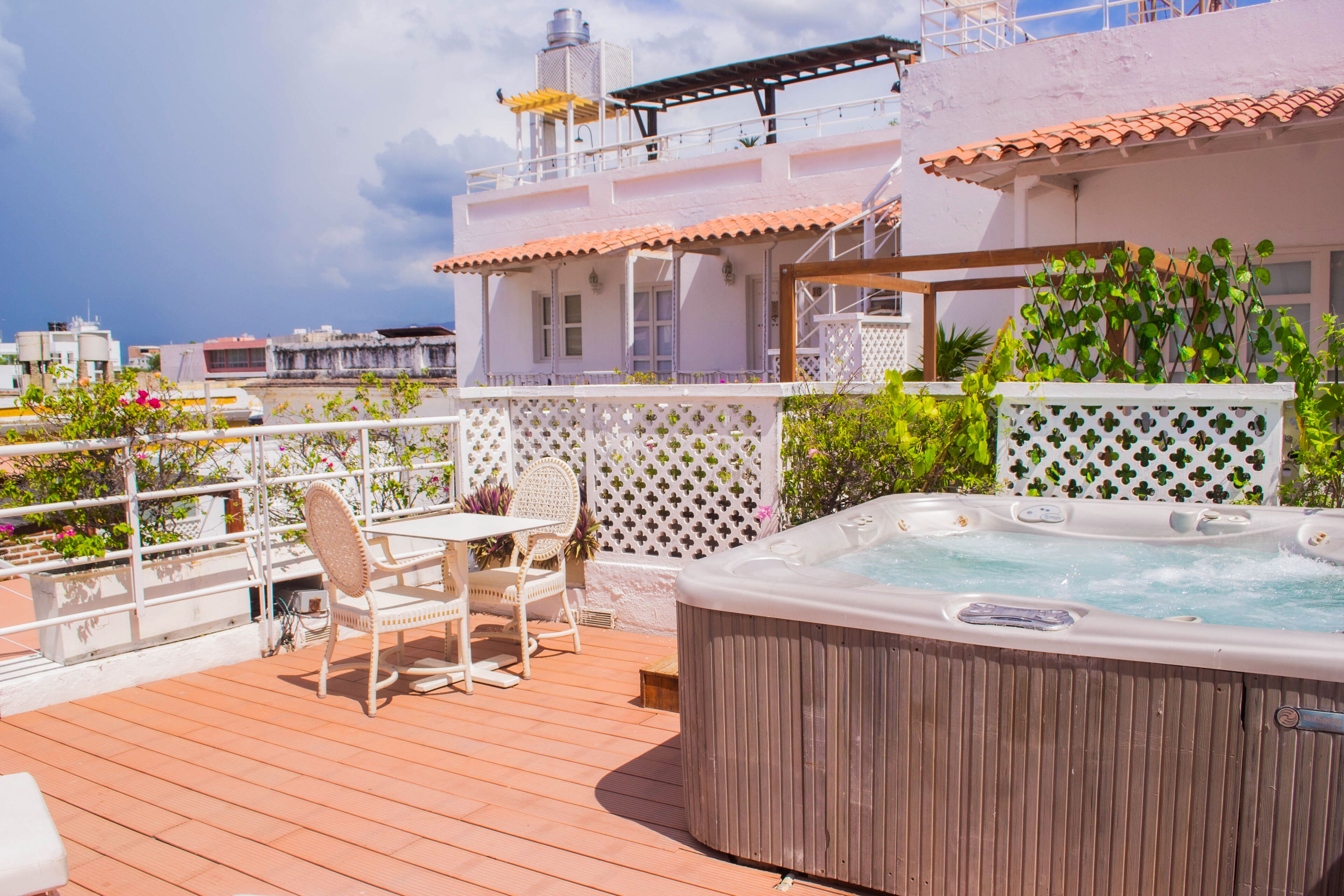 Una terraza en la azotea con hidromasaje, mobiliario exterior y vistas panorámicas de la ciudad.