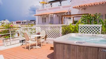 Una terraza en la azotea con hidromasaje, mobiliario exterior y vistas panorámicas de la ciudad.