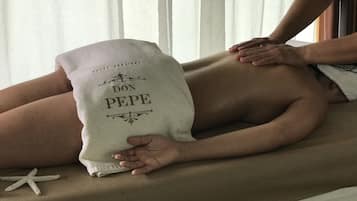 Una persona recibiendo un masaje en la espalda sobre una camilla con una toalla que dice "DON PEPE".