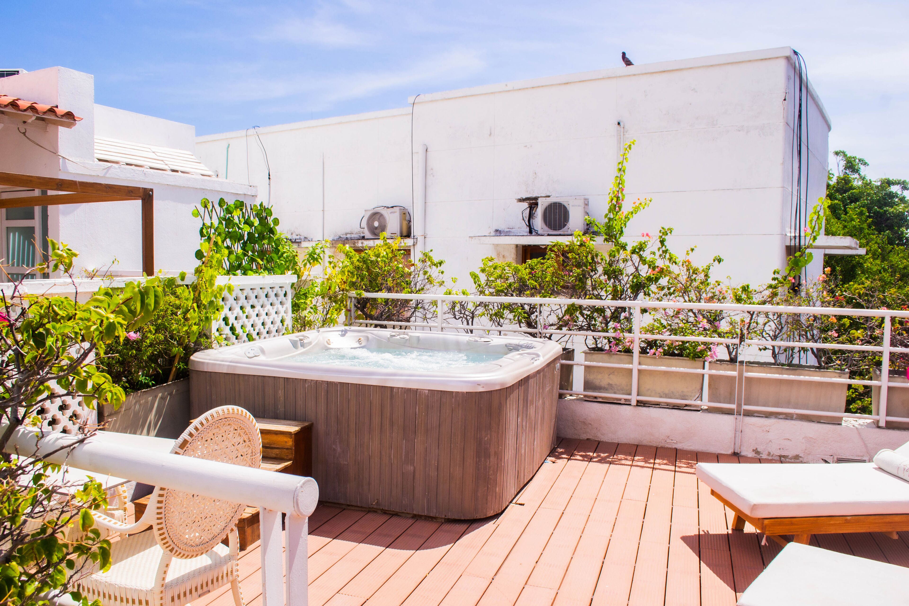 A rooftop patio with a hot tub, lounge chairs, and a pergola.