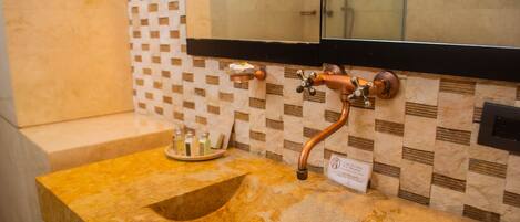 A bathroom with a marble sink, copper fixtures, and a tiled backsplash.