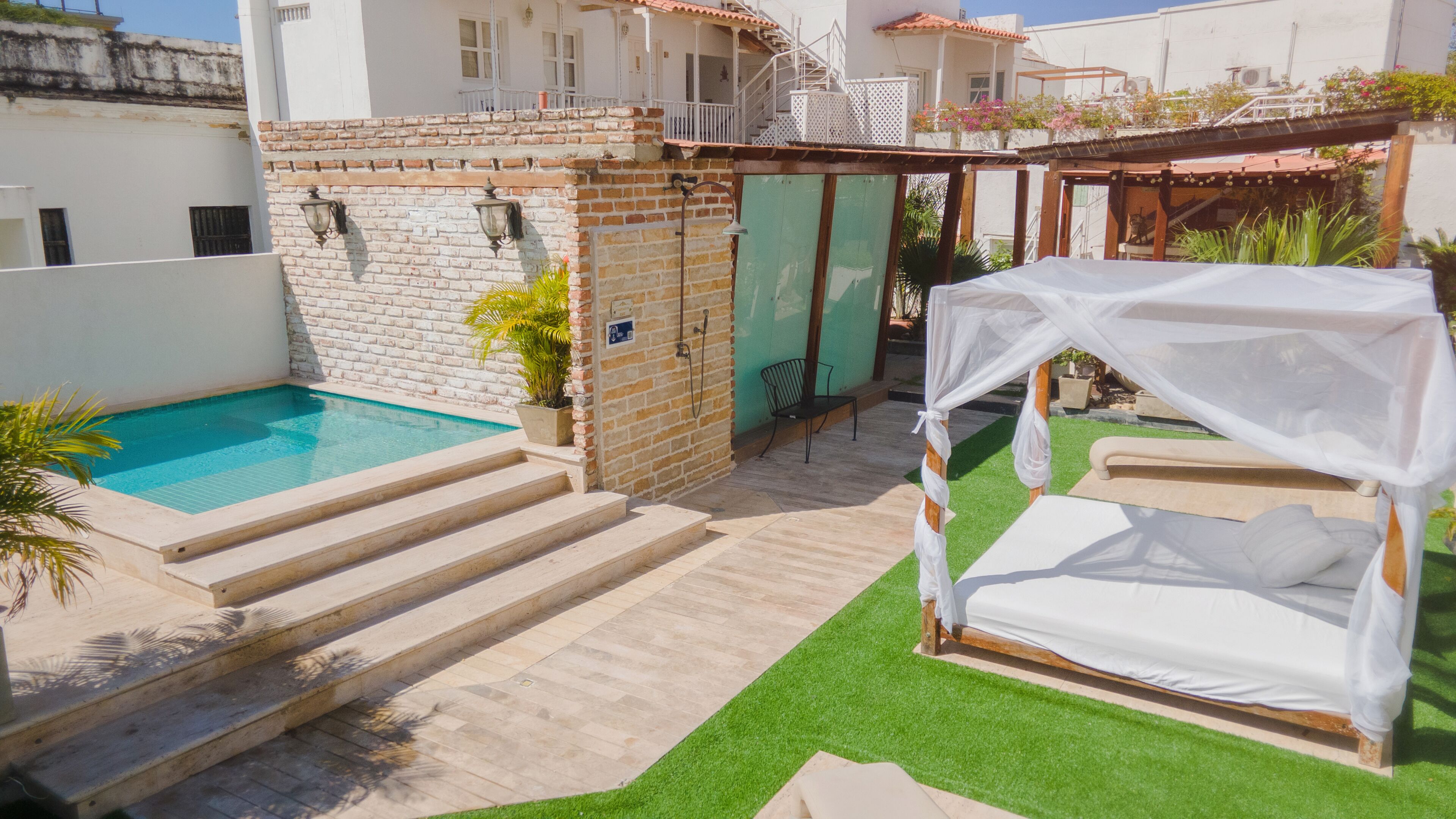 Un espace piscine avec des marches menant à un lit abrité.