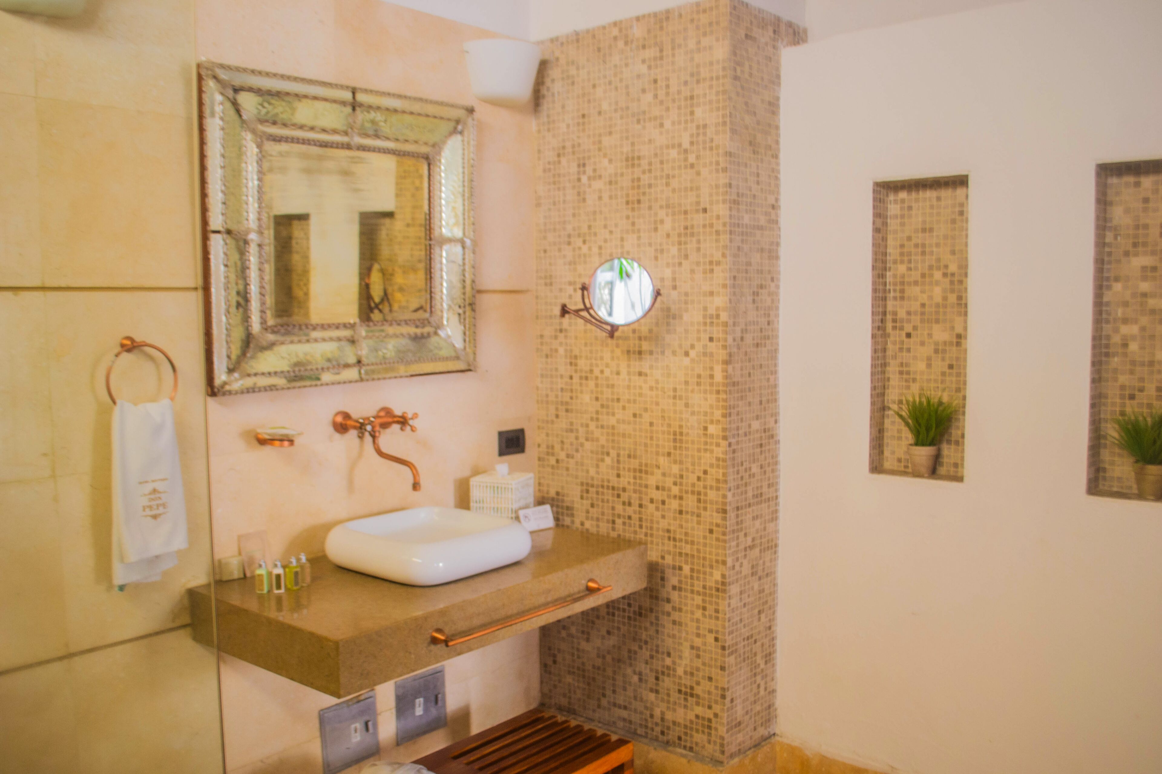 A bathroom with a large mirror, a sink, and a small round mirror on the wall.