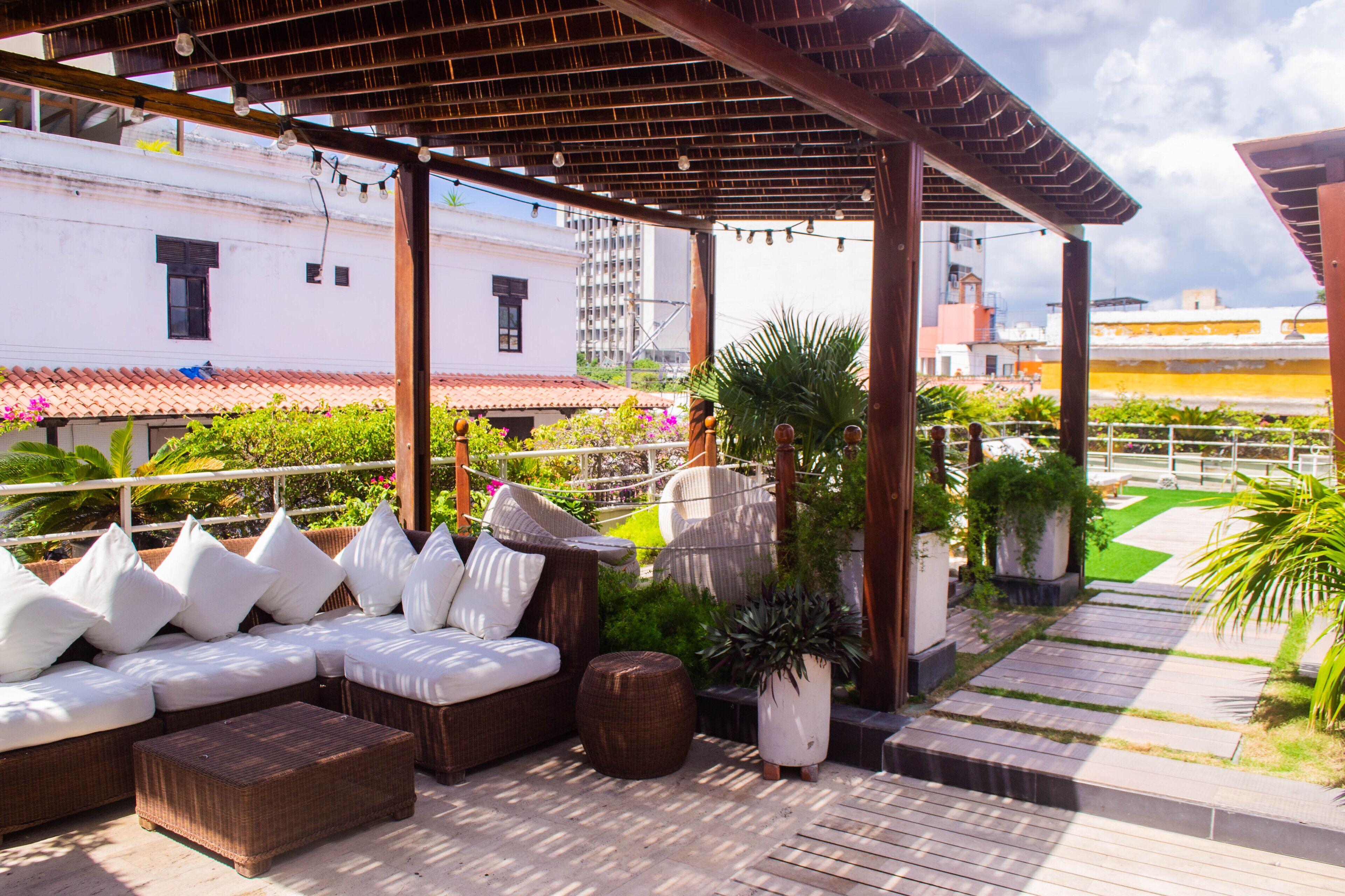 A covered outdoor seating area with wicker furniture and potted plants.