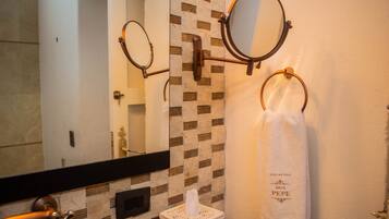 A bathroom with a mirror, towel rings, and a tissue box.