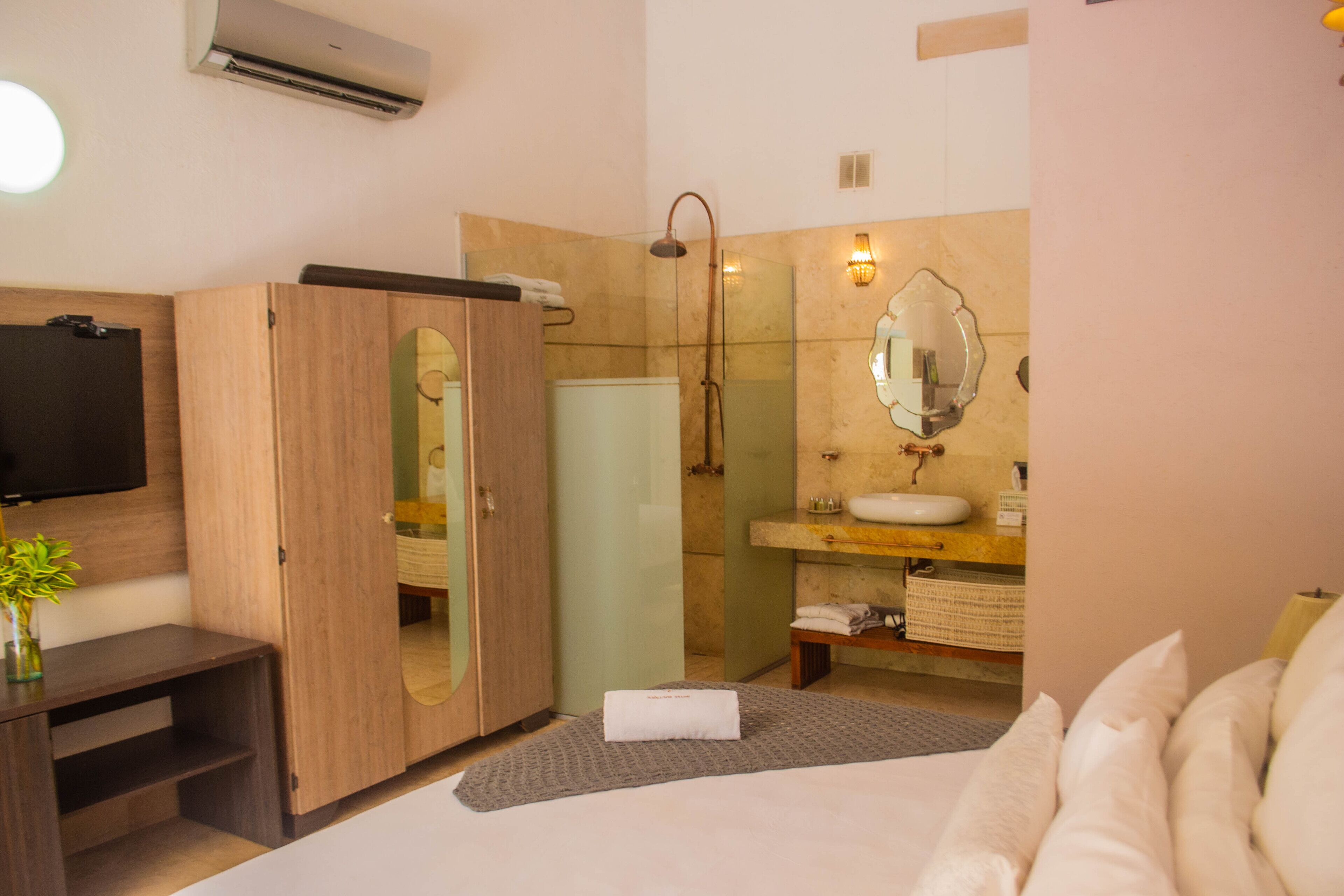 A modern bathroom with a glass shower enclosure, a vanity with a mirror, and a flat-screen TV mounted on the wall.