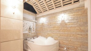 Un baño moderno con una bañera independiente, paredes de piedra y una zona de ducha con azulejos.