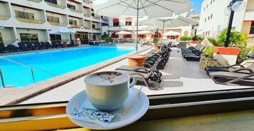 Una piscina al aire libre, sombrillas, sillones reclinables de piscina