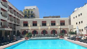 A pool area with lounge chairs and a clear blue sky.