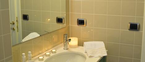A bathroom with a large mirror, a sink, and a green vanity. There are toiletries on the sink and a towel on the counter.