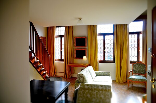 Una habitación con una escalera, un sofá, una silla, un escritorio y un televisor.
