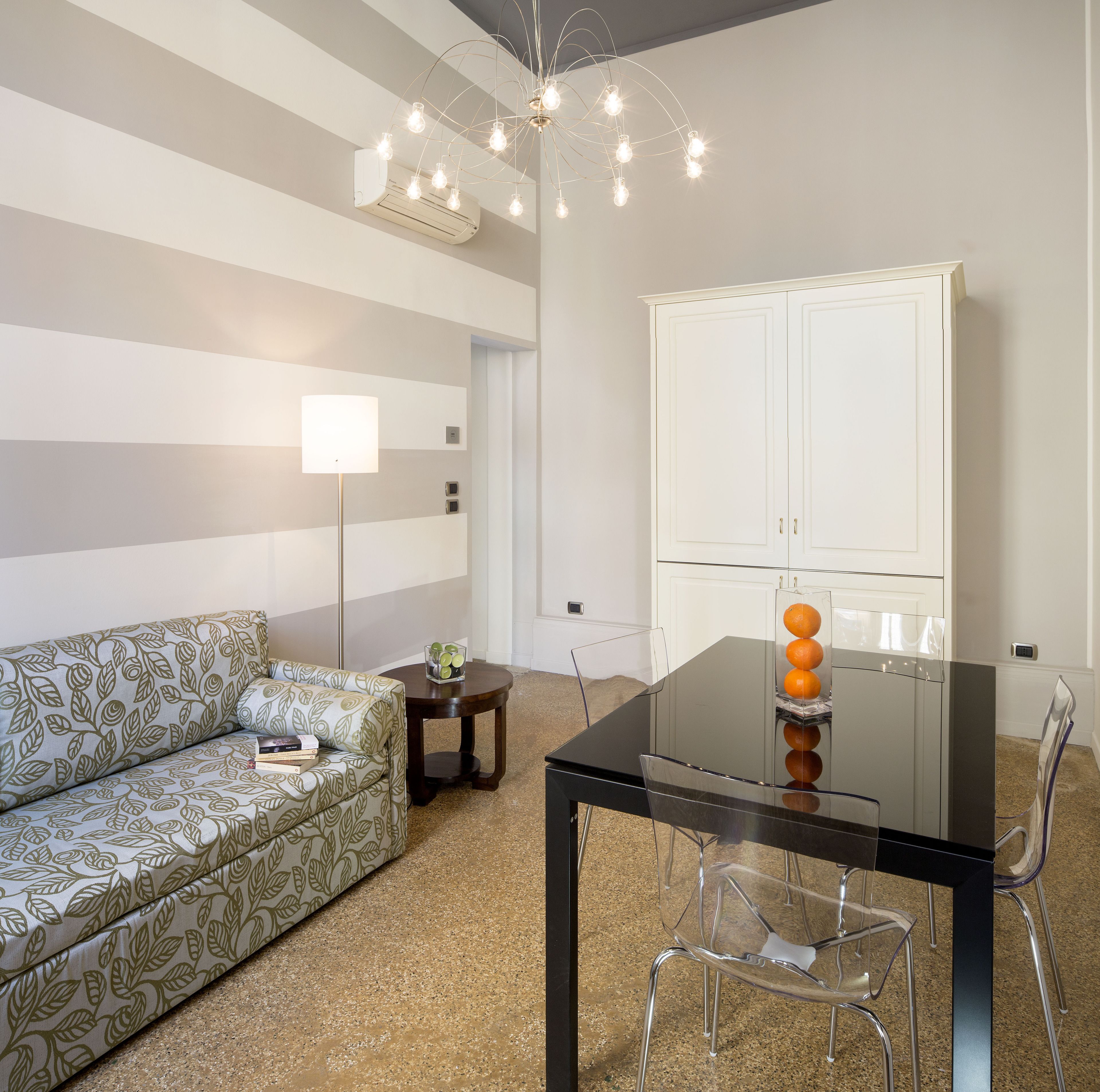 A modern living room with a sofa, a glass dining table, and a cabinet.