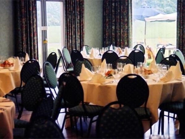 A dining area with round tables set for a meal, chairs, and a view of the outdoors. - Le Château de Limont (Donceel)