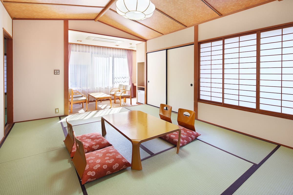 Una habitación tradicional japonesa con suelo de tatami, una mesa de madera baja y puertas correderas shoji.