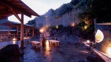 A stone patio with wooden benches and a bamboo fence.