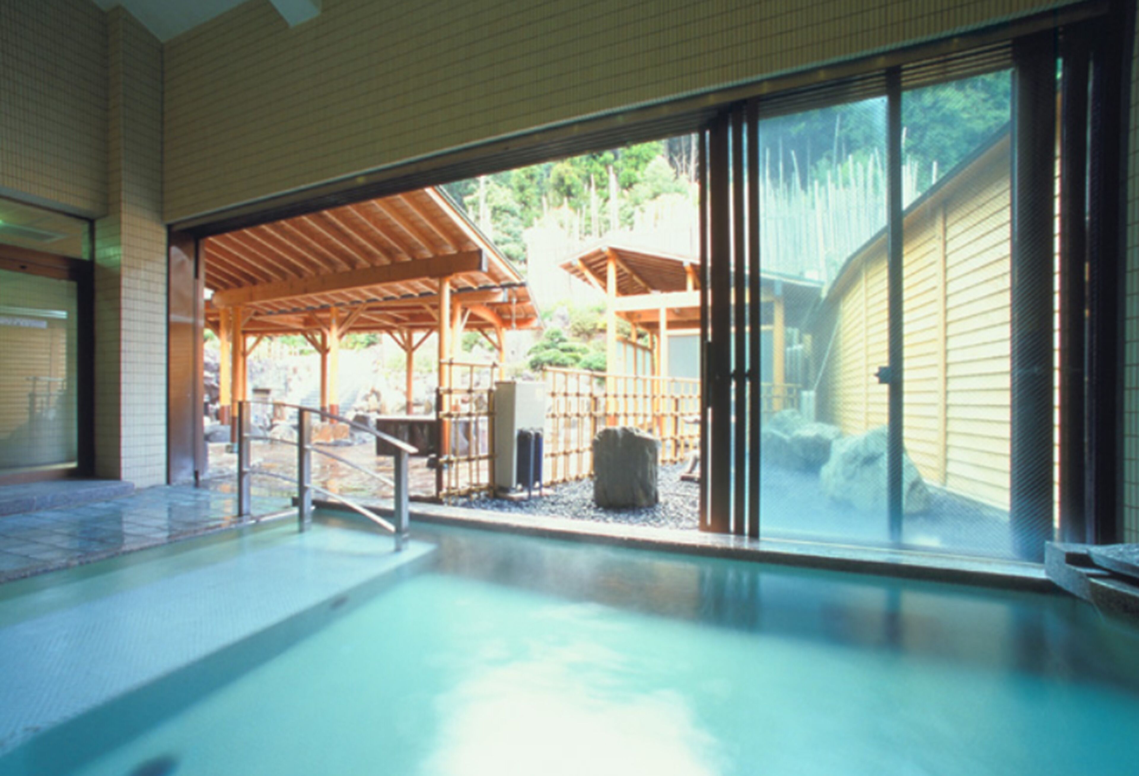 Une piscine intérieure avec vue sur une structure en bois et un espace extérieur abrité.