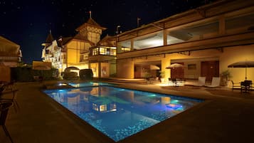 Una piscina al aire libre, sombrillas, sillones reclinables de piscina