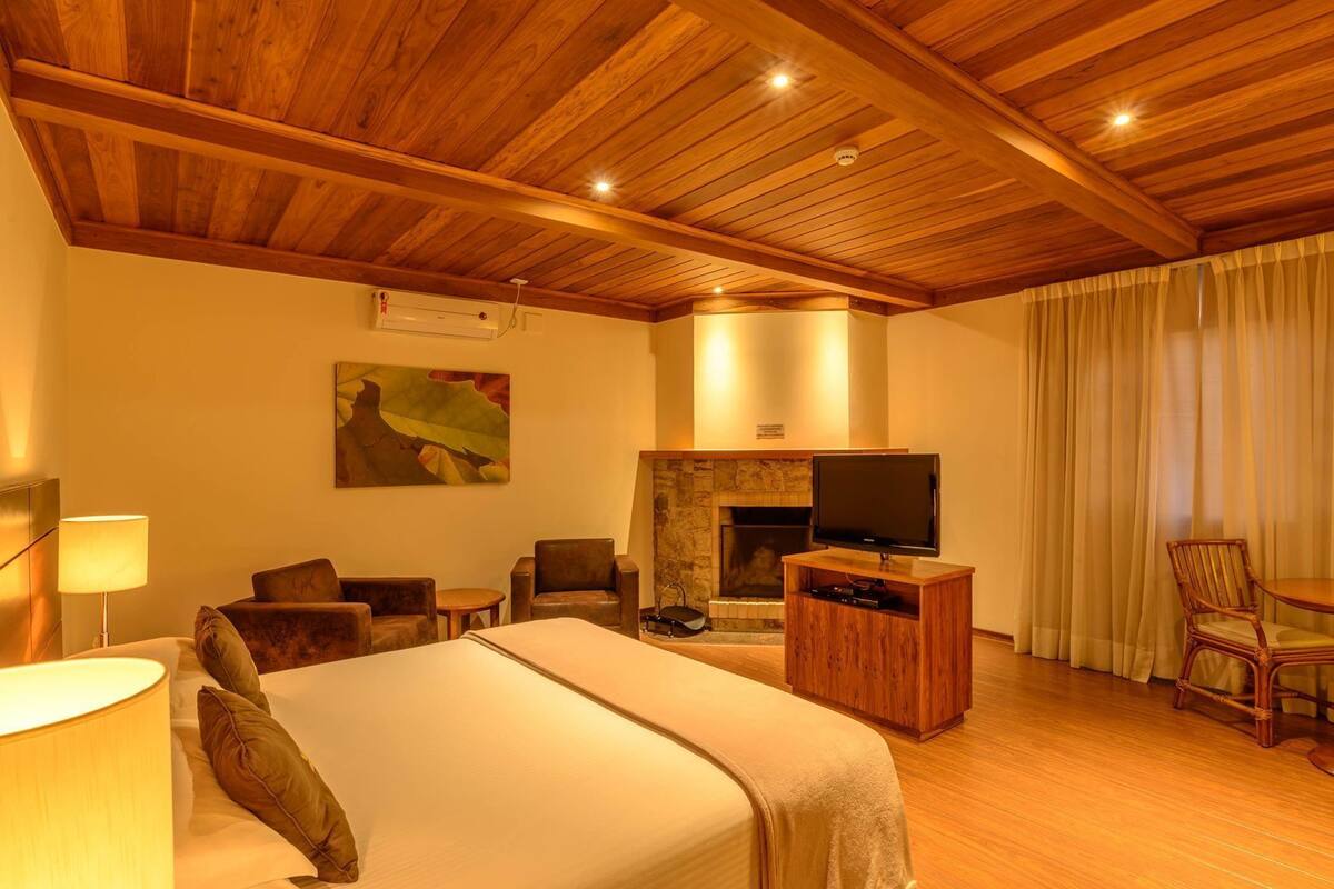 Ein Hotelzimmer mit Holzboden, Kamin, Fernseher, Bett und Essecke.