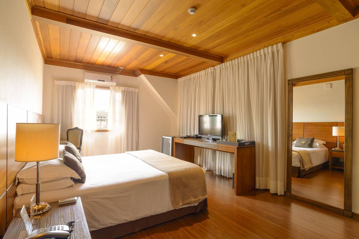 Ein Hotelzimmer mit Bett, Schreibtisch, Fernseher und Spiegel.