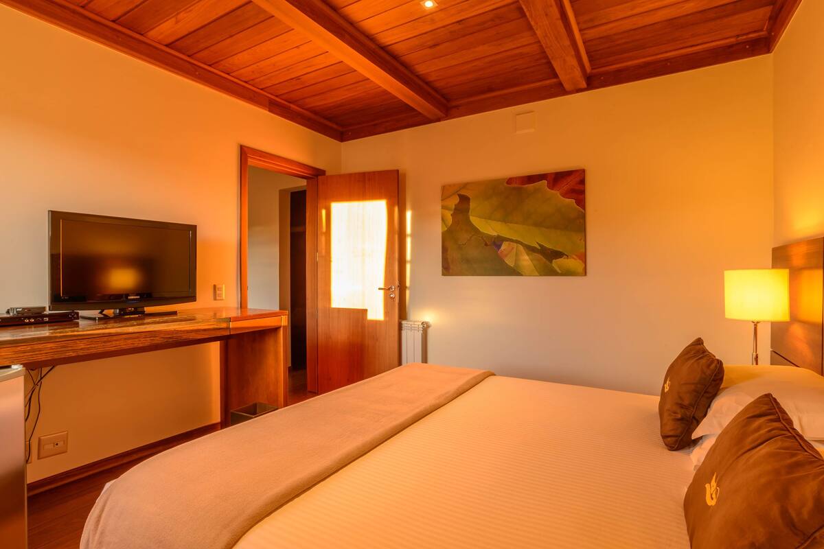 Ein Hotelzimmer mit einem Bett, einem Schreibtisch mit Fernseher und einem Bild an der Wand.