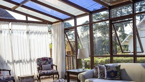Un invernadero con techo de cristal, amoblado con un sofá, un sillón y una mesa de centro.