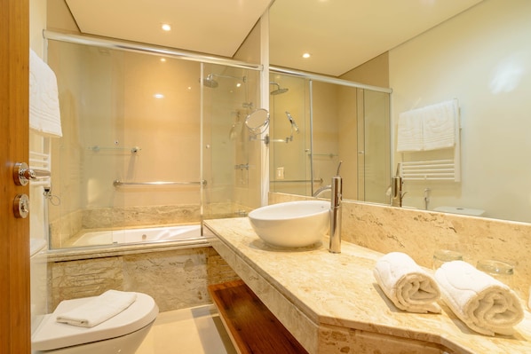 Un baño moderno con ducha envuelta en vidrio, un lavamanos grande y un inodoro.