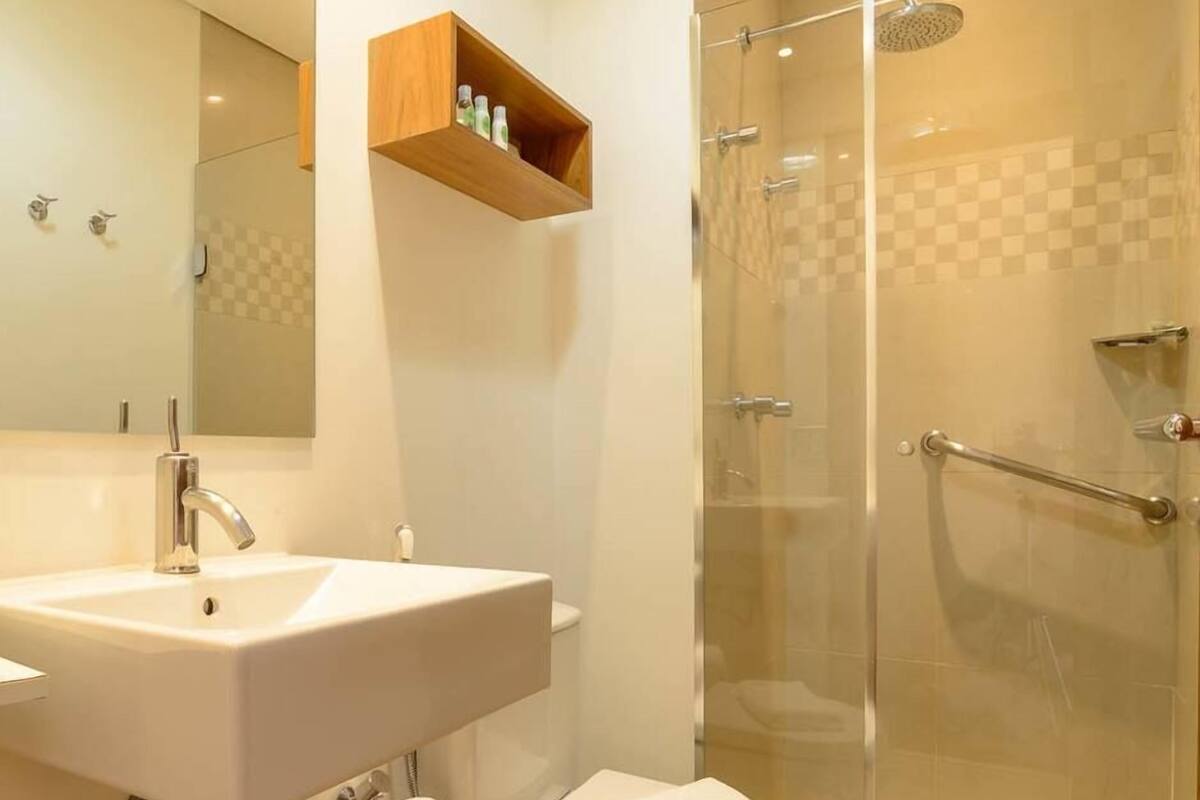 Ein Badezimmer mit Waschbecken, Spiegel, Dusche und Ablage für Toilettenartikel.