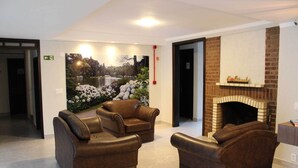 Un vestíbulo con sofás de cuero, chimenea y un mural que representa un paisaje lacustre.