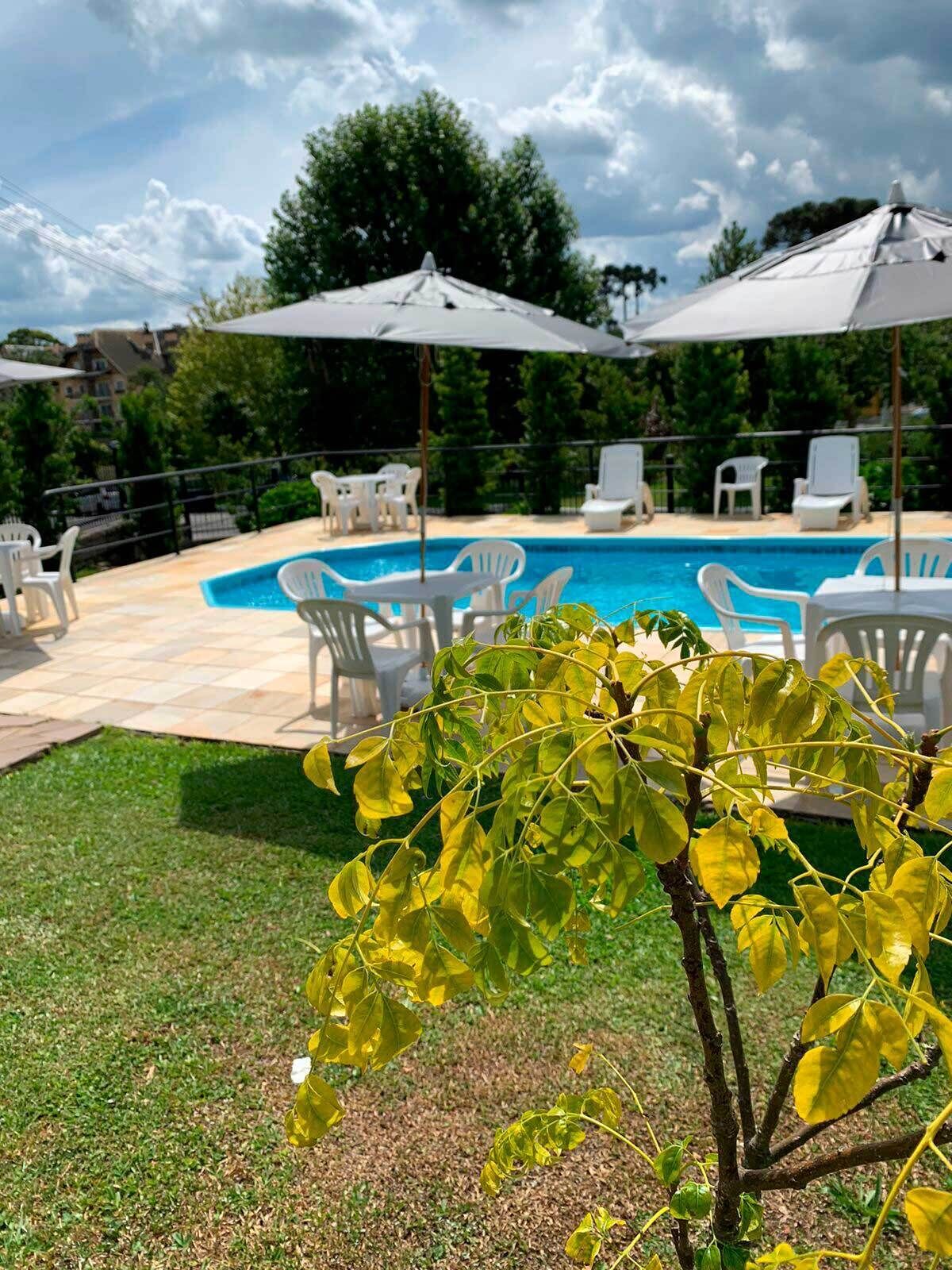 Una piscina al aire libre, sombrillas, sillones reclinables de piscina