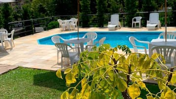 Una piscina al aire libre, sombrillas, sillones reclinables de piscina