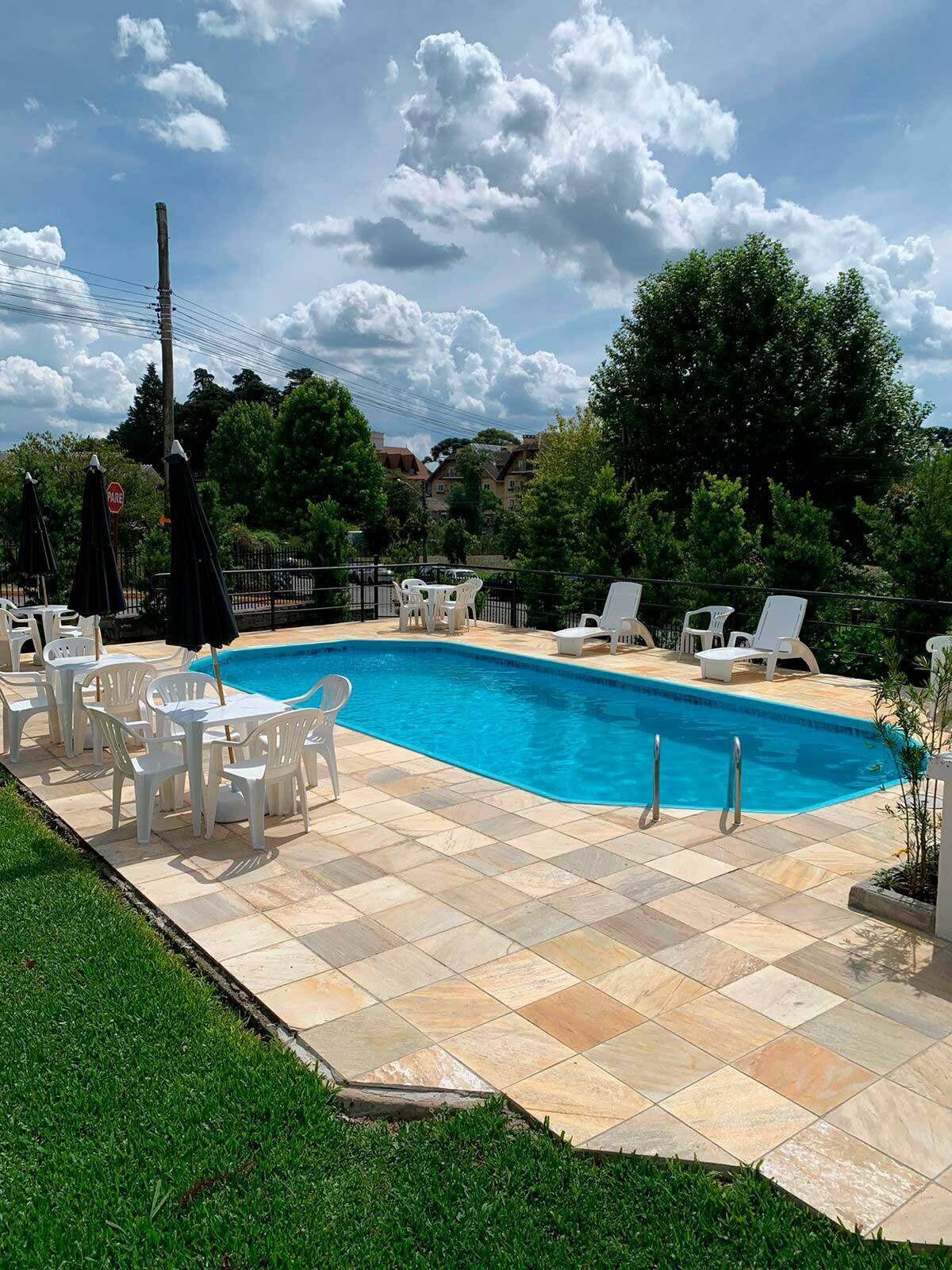 Una piscina al aire libre, sombrillas, sillones reclinables de piscina