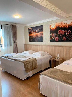 A hotel room with two beds, a wooden headboard, a nightstand with a phone, and two wall-mounted paintings. - Hotel San Lucas (Gramado)