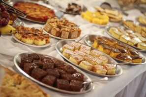 A buffet table with various desserts including cakes, brownies, and pastries. - Hotel San Lucas (Gramado)