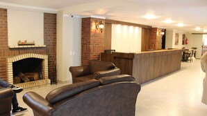 Una sala de estar moderna con chimenea, sofás de cuero y un mostrador de recepción de madera.