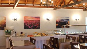 Un restaurante con vigas de madera, mesas, sillas e iluminación fijada a la pared.