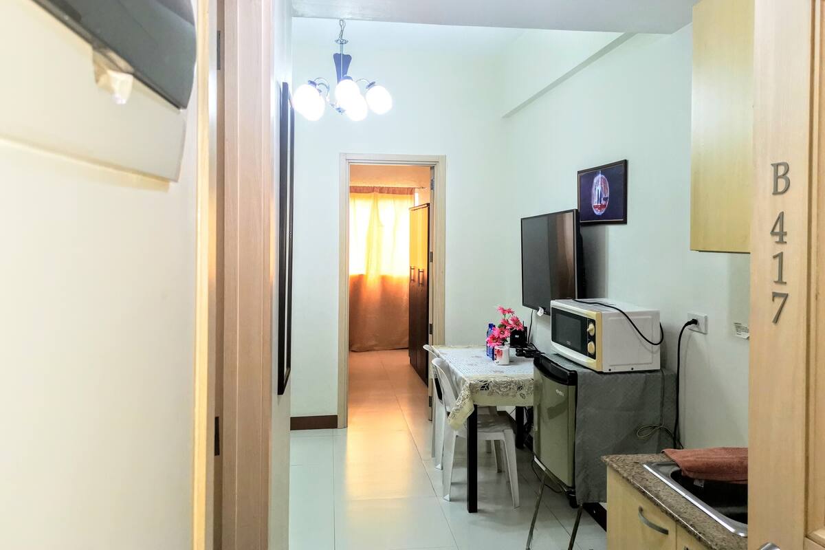A compact kitchen with a dining table, a microwave, and a television.