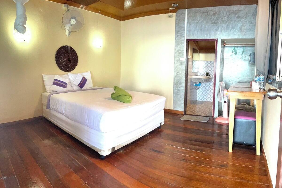 A bedroom with a bed, a bedside table, a mirror, and a door leading to a bathroom.