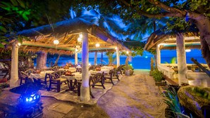 An outdoor dining area with tables and chairs, surrounded by trees and overlooking a beach. - Bottle Beach 1 Resort (Ko Pha-ngan)